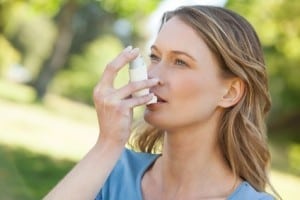 Woman using asthma inhaler in park